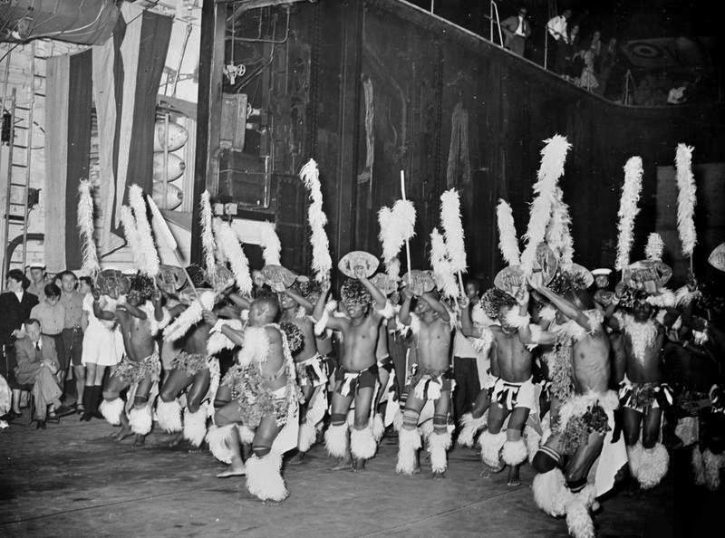 150 Zulus in native costume perform a Ngoma dance in the hangar of HMS Warrior, Durban, South Africa, November 1954