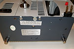 The lamp cover and adjustable leg assembly on the rear of the projector now needs to be removed. On the bottom of the projector, near the rear edge are are two sets of screws. The inner pair are slotted and the outer pair are Phillips. The inner slotted screws are the ones holding the lamp cover in place and need to be removed.